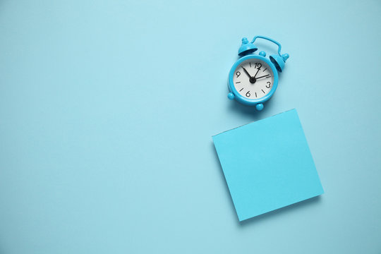 Blue alarm clock and a reminder note. Time management concept. Copy space for text.