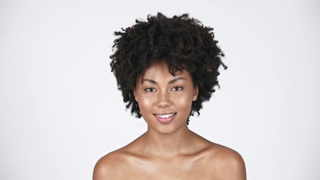 naked attractive african american girl smiling while looking at camera on white 