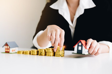 Businesswoman is holding house models and coins concept of Real Estate, home loan, installment loan, loan interest