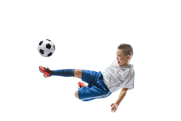 Young boy kicks the soccer ball. Isolated photo on white background. Football player in motion at studio. Fit jumping boy in action, jump, movement at game.