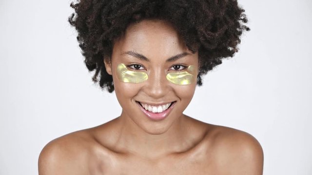 beautiful african american girl touching eye patches and smiling on white 