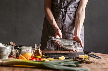 woman chef preparing fresh raw dorado fish