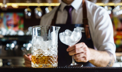 Expert barman is making cocktail at night club