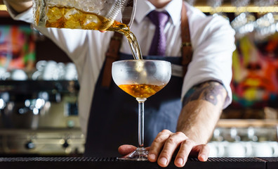 Expert barman is making cocktail at night club