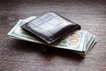 Brown leather men's wallet with money. Purse with a pack of 100 dollar bills. The concept of good luck and good money making.