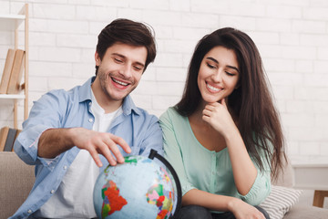 Happy couple with globe choosing place for holiday