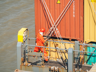 Deck worker on the vessel hold on containers.