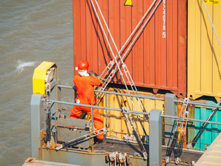 Deck worker on the vessel hold on containers.