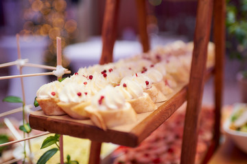 Tasty creamy snacks on the wooden plate in a restaurant. An amazing bokeh on the background.