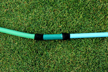 a green hose lying on the grassy ground, A close up image of a garden hose, Rubber tube for watering plants in the garden.