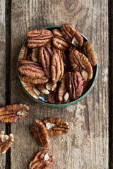 Pecan nuts on a rustic wooden table and pecan nuts in bowl.