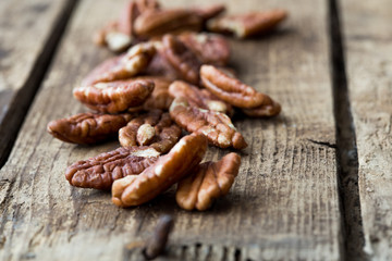 Pecan nuts on a rustic wooden table and pecan nuts in bowl.