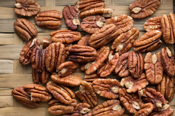 Pecan nuts on a rustic wooden table and pecan nuts in bowl.