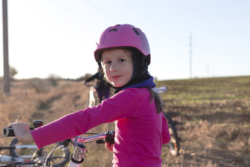 Portrait of a little girl in a helmet with a bicycle
