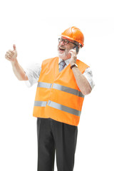The builder in a construction vest and an orange helmet talking on a mobile phone about something. Safety specialist, engineer, industry, architecture, manager, occupation, businessman, job concept