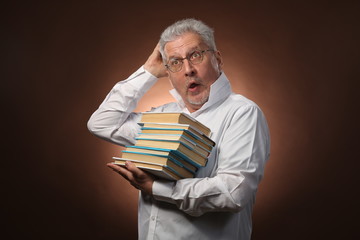 Scientific thinker, philosophy, elderly gray-haired man in a white shirt with a books, with studio light