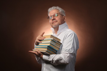 Scientific thinker, philosophy, elderly gray-haired man in a white shirt with a books, with studio light