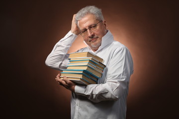 Scientific thinker, philosophy, elderly gray-haired man in a white shirt with a books, with studio light