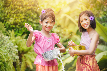 Songkran day with thai girls children playing splash water in songkran festival with thai period...