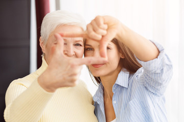 Happy mom and daughter making frame with fingers