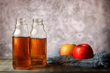 On the table is apple juice in a glass bottle