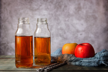 On the table is apple juice in a glass bottle
