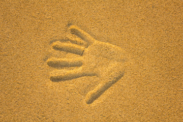 right hand print in yellow sand close up