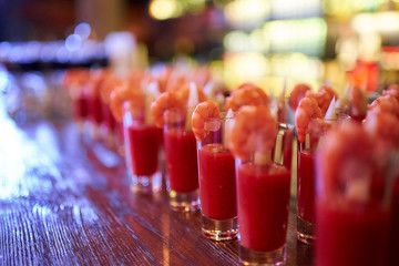 Snacks in glasses of tomato sauce with shrimps in a nightclub