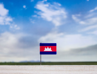 Flag of Cambodia with vast meadow and blue sky behind it.