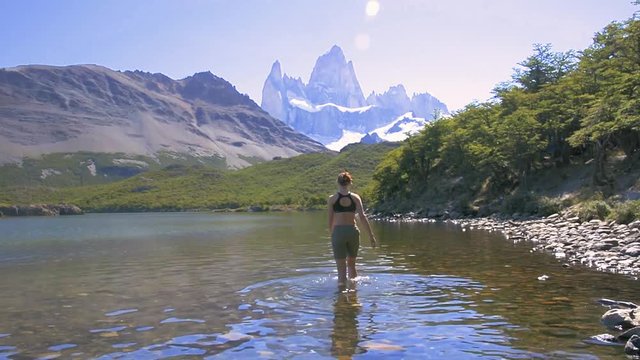 Young woman walking in the lake in Laguna Carpi, looking at the Fitz Roy in Patagonia, Argentina. Trekking around Fitz Roy near El Chalten, Argentina. Travel and adventure concept.