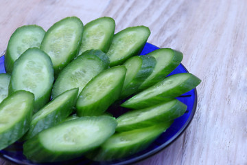 Fresh green thinly sliced cucumber on a blue plate.
