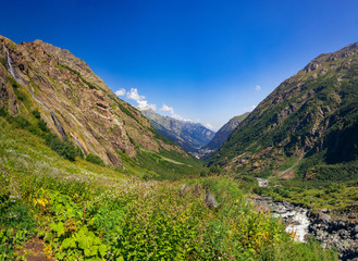 Alpine river with huge cobblestones in the surroundings of Dombai on a summer day.