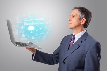 Man holding laptop projecting cloud based system symbols and informations