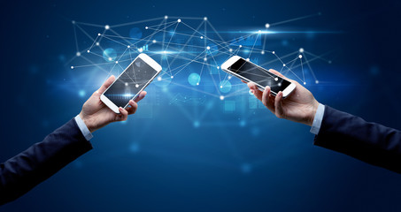 Close up of two hands holding smartphones and sharing business data