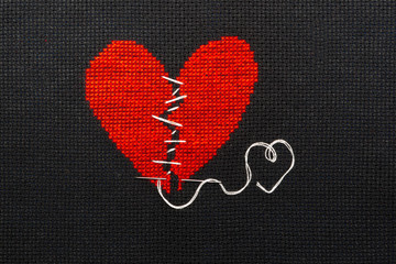 The broken heart is embroidered with red threads on a black cloth.