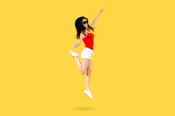 jumping girl in sunglasses and a red shirt on a yellow background, concept summer mood