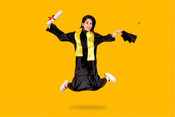 Obraz premium graduate student with a diploma in jumping on an orange background, success learning concept