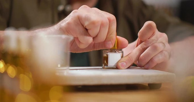 Close up of perfumer screwing small bottle with perfume