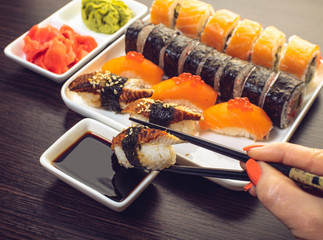 sushi with eel dipped in soy sauce