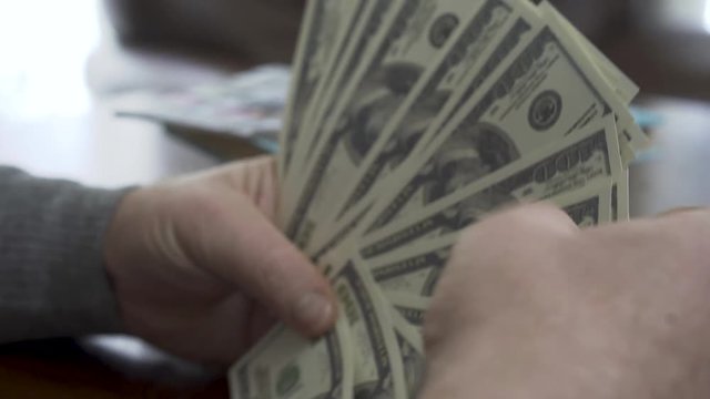 Hands of the old man counting dollars close up. Positive rich man demonstrates his money. Leisure of prosperous retired man. Great business deal