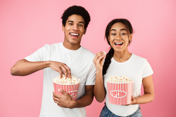 African-american teen couple eating popcorn, watching movie