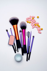 Top view of make-up brushes, blush and vitamin pills on a white background. Beauty and healthy concept
