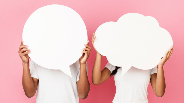 Couple holding empty speech bubbles, pink background