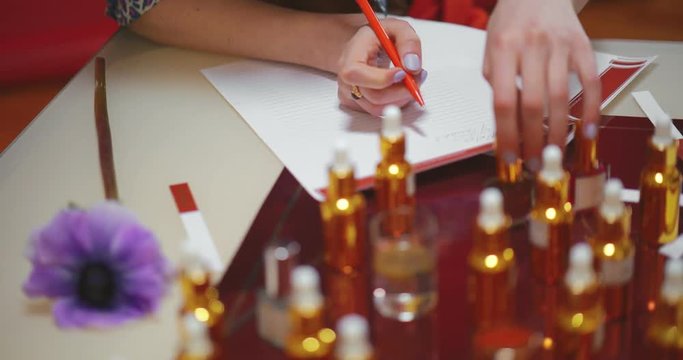 Close up of woman choosing essential oils and writing down