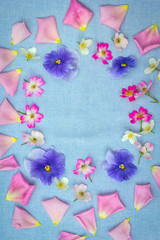 Beautifuil, natural frame with violet pansies and pink roses on blue, fabric background