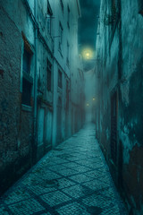 schmale alte und unheimliche Straße mit schäbigen, baufälligen Häusern und schwachen Laternen in einer mittelalterlichen Stadt bei Nacht