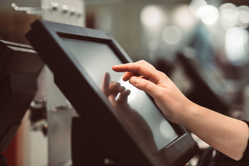 Obraz premium Młoda kobieta robi płatność procesową w kasie z ekranem dotykowym, koncepcja finansów (obraz stonowany kolor)