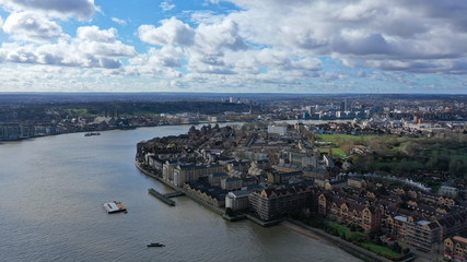 Obraz premium Aerial bird's eye view photo taken by drone of Canary Wharf skyline as seen from river Thames with beautiful cloudy sky, Isle of Dogs, London, United Kingdom