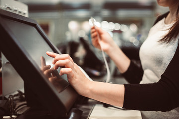 Young woman hand doing process payment on a touchscreen cash register, finance concept (color toned...