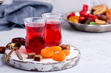 Fruit tea in turkish glasses and oriental sweets, dates and dried apricots. High key